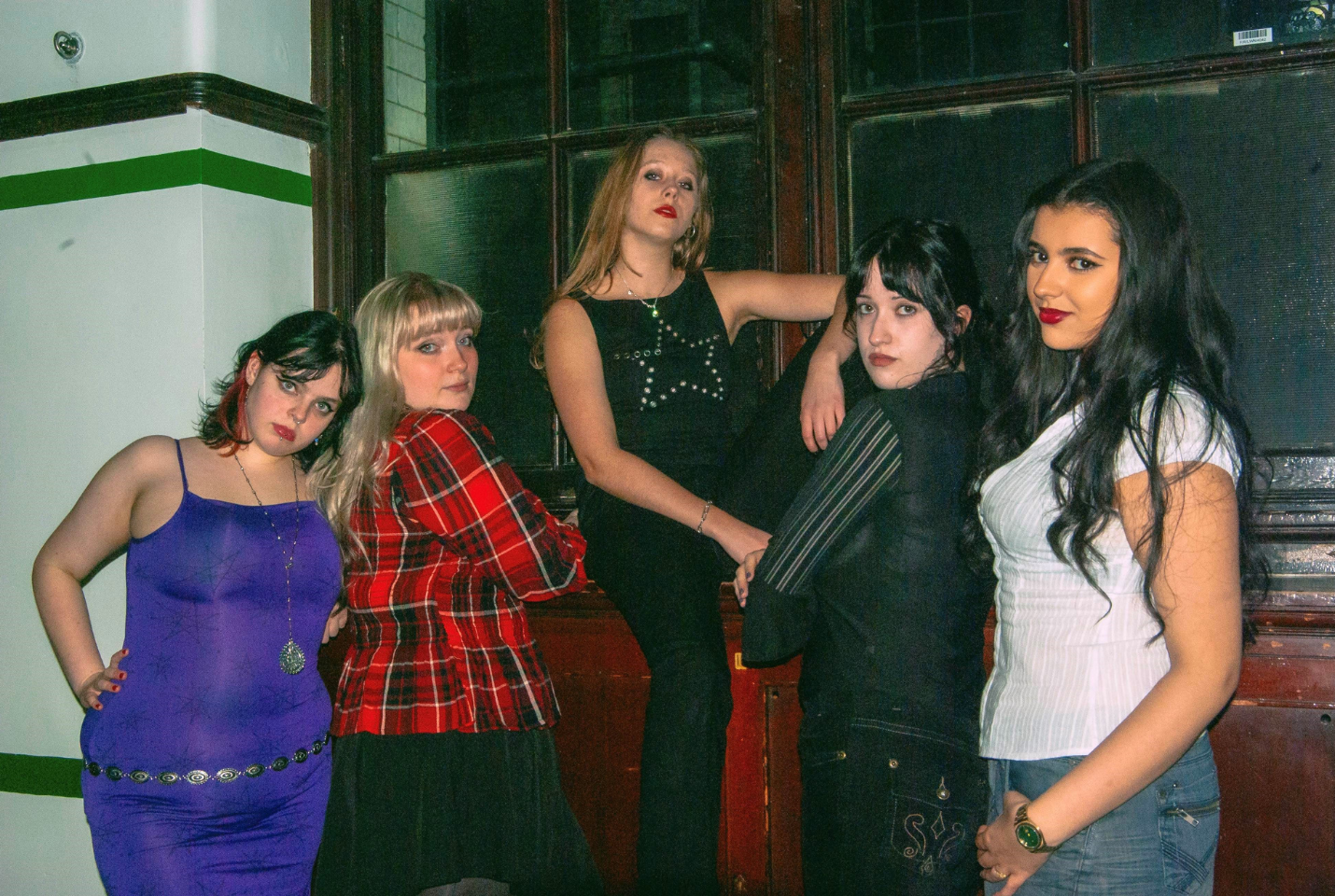 Five members of Diva Down posing in front of a window 